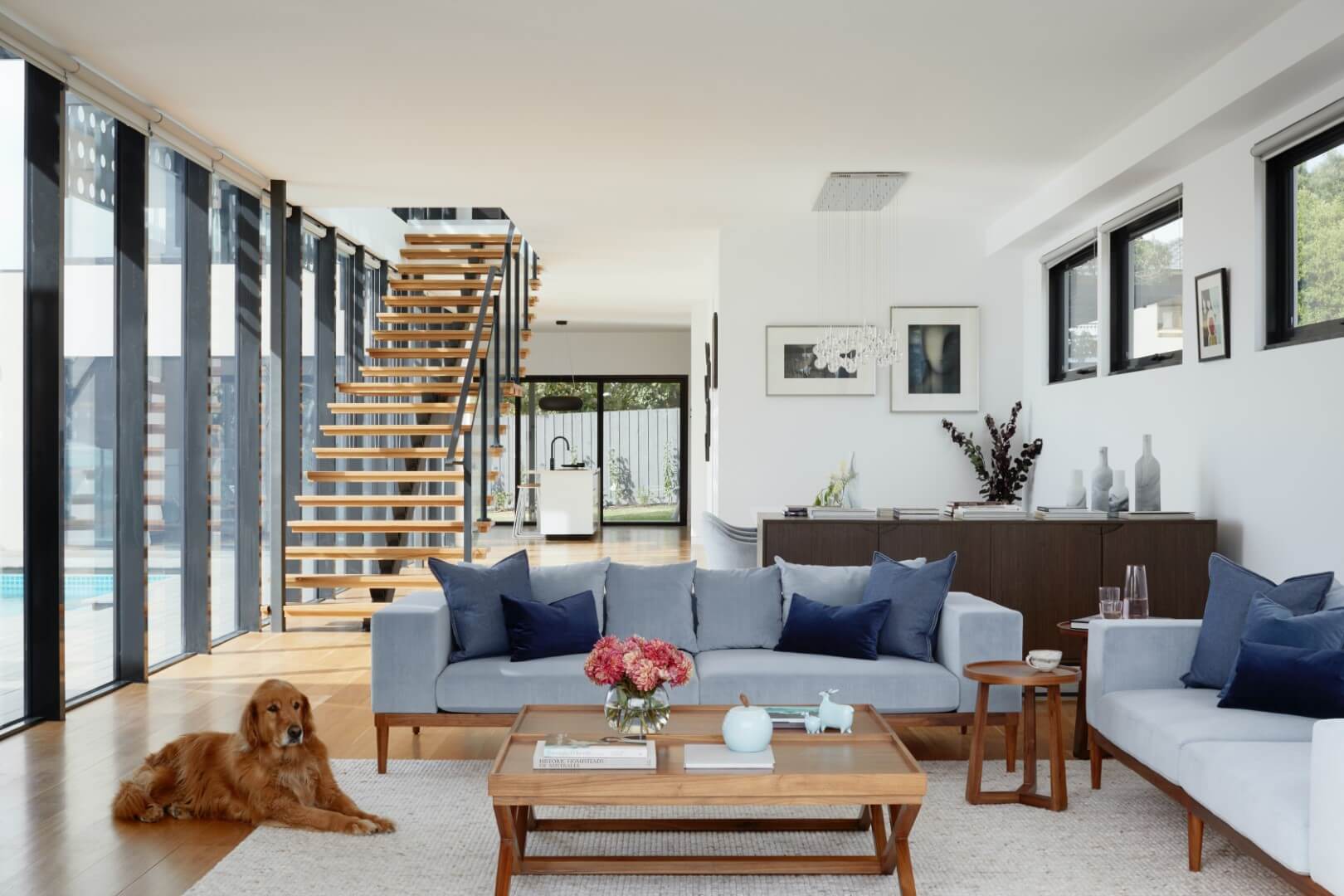 Big living room with huge windows, stairs and a dog