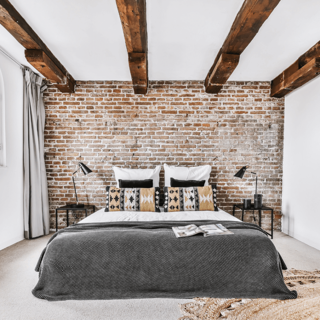 Industrial bedroom, bed with black matress and a wall with natural brick colors